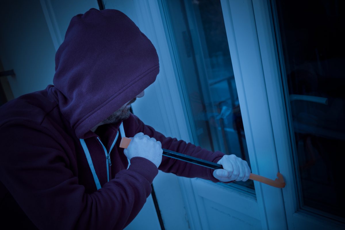 man trying to break into window with security film installed on it